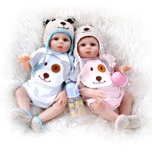 Lifelike reborn baby dolls in pink and blue dog print outfits on white plush rug