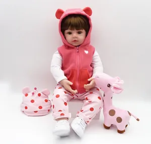 Detailed view of reborn baby doll in pink vest with matching giraffe plush toy