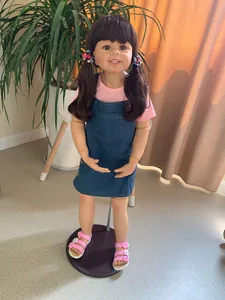 Detailed full-body shot of 98cm realistic girl doll in pink shirt and denim overall dress