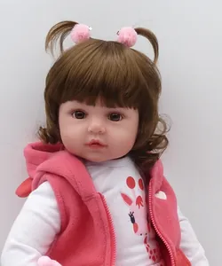 Close-up of lifelike reborn baby doll with curly brown hair and pink fleece hoodie vest