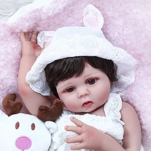 Lifelike 47cm reborn baby doll with brown hair and lace outfit on pink blanket