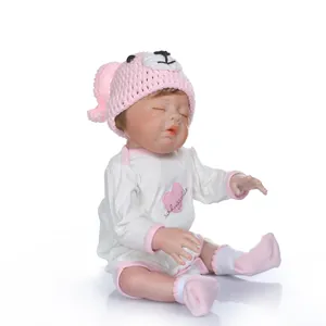 Dettaglio di una bambola Reborn che dorme con cappello rosa e tutina morbida bianca
