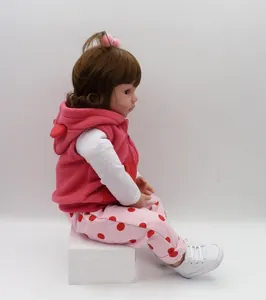Side view of 47cm reborn baby doll wearing a pink hooded vest and white sneakers