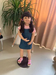 Detail of 98cm girl doll featuring dark brown pigtails with floral hair accessories