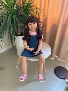 Close-up of a 98cm realistic toddler doll with brown pigtails and pink floral outfit