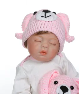 Dettaglio di una bambola neonata che dorme con cappello a maglia rosa e orso