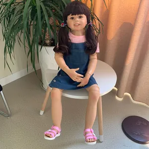 Detail of 98cm girl doll with brown pigtails wearing pink shirt and denim overalls