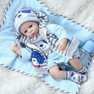 Lifelike reborn baby doll in blue striped outfit with hat, socks, and feeding bottle