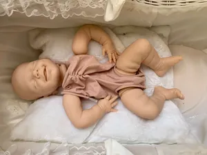 Detailed view of closed-eye reborn baby doll head in a soft pink cotton bodysuit