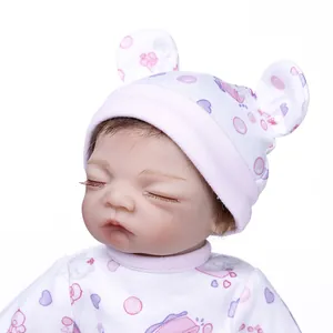Close-up of a 30cm sleeping reborn baby doll with cute bear ear hat and floral outfit