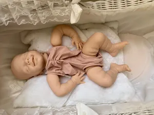 Detail of reborn doll in a lace-trimmed woven cradle with a soft pink romper
