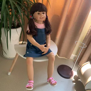 Detail of 98cm realistic toddler doll with brown pigtails sitting on a white chair
