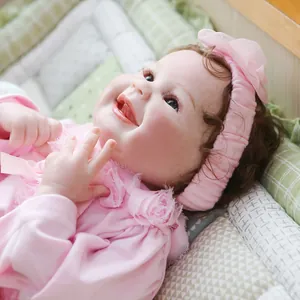 Lifelike reborn baby doll with smiling face, pink lace outfit and floral headband