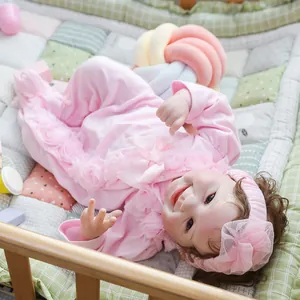 Lifelike reborn baby doll with smiling face wearing pink lace outfit in a cradle
