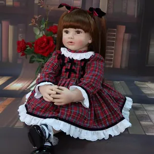 Realistic reborn toddler doll in red plaid dress with white lace and black bow