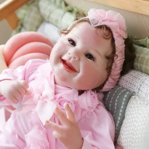 Realistic reborn baby doll with curly brown hair wearing a pink lace romper and headband