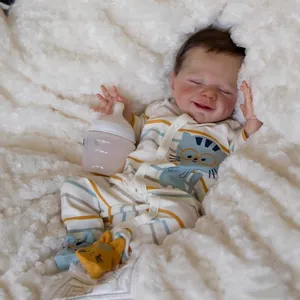 Realistic sleeping reborn doll in striped cat outfit with bottle on white plush blanket