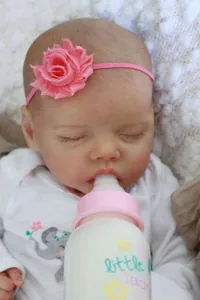 Close-up of lifelike reborn baby doll wearing elephant print onesie and flower headband