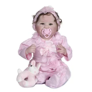 Realistic reborn baby doll with smiling face, pink lace outfit and plush rabbit toy
