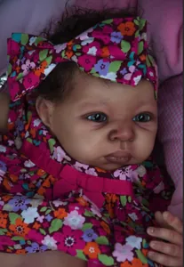 Vue détaillée de la poupée reborn à la peau foncée avec robe florale et nœud papillon