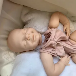 Smiling reborn baby doll April in mauve knit bodysuit on soft plush white bedding