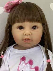 Close-up of a 55cm reborn toddler doll with long brown hair and pink bow accessory