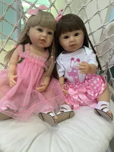 Close-up of two realistic reborn toddler dolls sitting in a white woven hanging chair