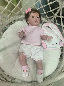 Λεπτομερής κοντινή λήψη της κούκλας reborn Saskia σε ροζ σύνολο μέσα σε πλεκτή κούνια