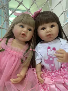Close-up of two realistic reborn toddler dolls with fine facial details and diverse outfits