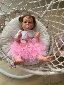 Detail of 55cm Reborn doll in pink tutu dress sitting in a white woven hanging chair