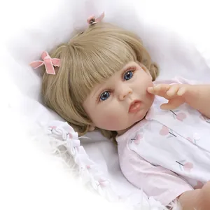 Close-up of a 47cm reborn doll girl with golden hair, pink bows, and blue realistic eyes