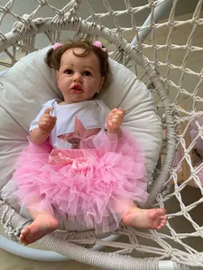 Close-up of realistic reborn toddler in pink tutu sitting in a white hanging chair