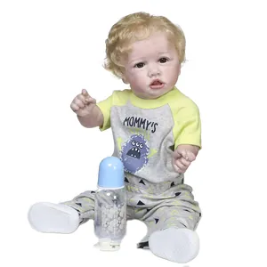 Realistic reborn toddler boy doll with blonde curls in yellow monster romper and bottle