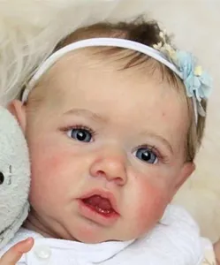Close-up of lifelike 22-inch Reborn Baby Saskia with blue eyes and floral headband