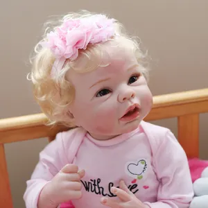 55cm reborn baby doll with blonde curls and pink outfit lying in a wooden crib