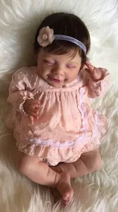Detailaufnahme einer 22-Zoll Reborn-Puppe mit geschlossenen Augen und rosa Kleid