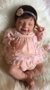 Detailansicht der 22 Zoll schlafenden Reborn-Puppe im rosa gepunkteten Kleid auf Fell