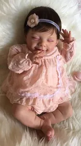 Detailansicht der schlafenden Reborn-Puppe im rosa gepunkteten Kleid mit Spitze