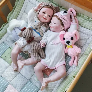 Bambole reborn realistiche da 22 pollici in abiti rosa e bianchi in una culla di legno