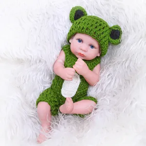 Realistic 26cm baby doll in green handmade crochet frog outfit on white plush rug