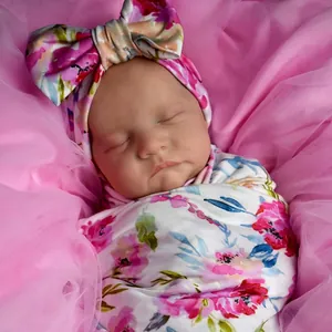 Lifelike 19-inch reborn baby doll in floral swaddle wrap with matching bow headband