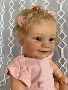 Close-up of realistic newborn doll featuring blonde curly hair and pink floral headband