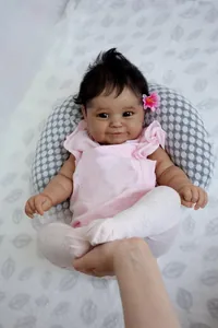 Dettaglio di bambola reborn da 50cm con capelli neri, fiore rosa e calze a maglia