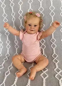 Close-up of realistic newborn baby doll with floral headband and pink ruffled outfit