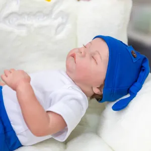 Close-up of sleeping reborn baby doll with detailed skin texture and blue knit hat