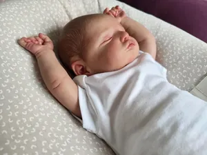Macro shot of sleeping Reborn Baby Doll Rosalie with lifelike skin texture and baby bodysuit