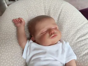 Close-up of sleeping reborn baby doll Rosalie with realistic skin and white bodysuit