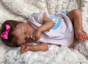 Close-up of sleeping reborn doll showing realistic skin texture and pink hair bow