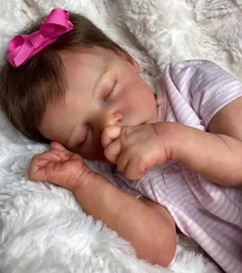 Close-up of sleeping reborn doll with lifelike skin texture and pink bow headband