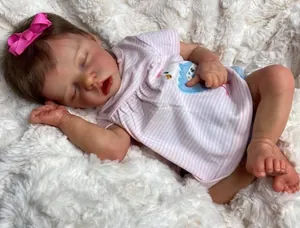 Close-up of sleeping 18-inch reborn doll with realistic skin and pink bow headband